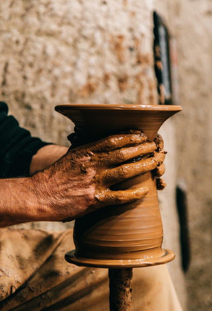 vase being turned on a wheel with clay caked hands. Photo by Meruyert Gonullu.